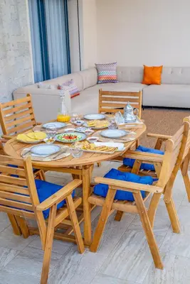a wooden table and chairs with plates and food on it at Villa Elysée - Piscine et jardin Privée Sans vis-à-vis Wifi HD in Sraghna