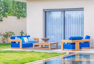a patio with blue couches and tables next to a pool at Villa Elysée - Piscine et jardin Privée Sans vis-à-vis Wifi HD in Sraghna