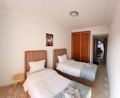 a bedroom with two beds and a table at Apartement Gueliz Marrakech in Marrakech