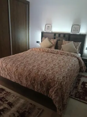 a bedroom with a bed with a brown comforter and pillows at marrakech semlalia gueliz in Marrakech