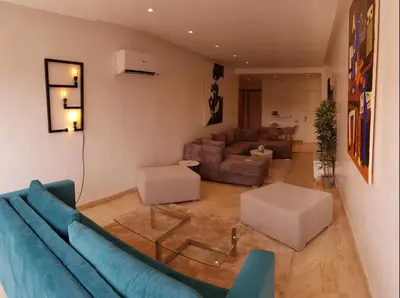 a living room with a blue couch and a living room with a couch at Urban Chic 2 bedrooms in Utimate City Center in Marrakech