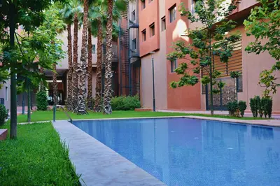 a swimming pool in front of a building with trees at Appartement De Luxe Avec Piscine a Marrakech in Marrakech