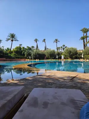 a large swimming pool with palm trees in the background at Marrakech Palmeraie 2 appt 2ch, résidence avec piscine in Marrakech