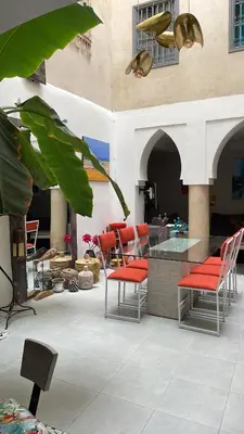 a patio with red chairs and a glass table at Riad Dom in Marrakech
