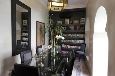 a dining room with a table and black bookshelves at Dar Lysis private with pool and breakfasts in Marrakech
