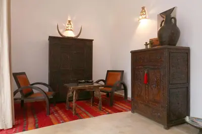 a room with a table and chairs and a wooden cabinet at Riad XCIX, basin, 3 bedrooms in Medina excluded in Marrakech
