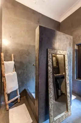 a mirror on a wall in a room with a chair at Riad XCIX, basin, 3 bedrooms in Medina excluded in Marrakech