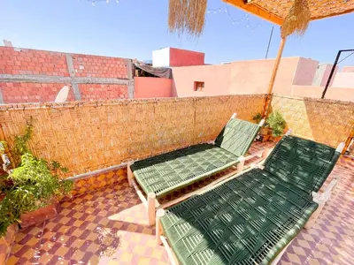 two green chairs and an umbrella on a patio at Smile Hostel in Marrakech