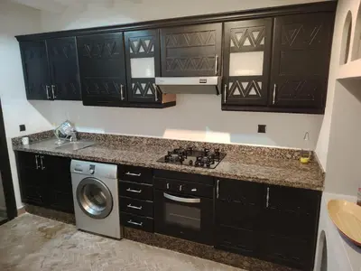 a kitchen with black cabinets and a washing machine at Family apartement at Premium village in Marrakech
