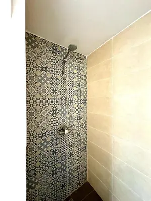 a shower in a bathroom with a tile wall at Riad Nabil with Concierge and FREE Breakfast in Marrakech