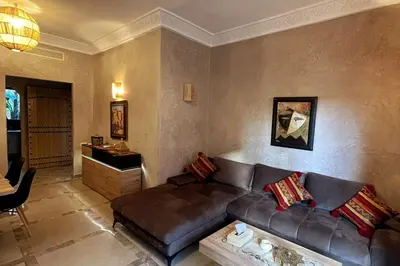 a living room with a leather couch and a table at Atlas Gardens Apartment in Sraghna