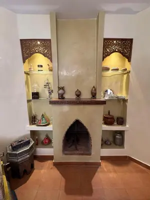 a living room with a fireplace and shelves of pottery at Authentic Family Apartment Riad stylein Gueliz in Marrakech