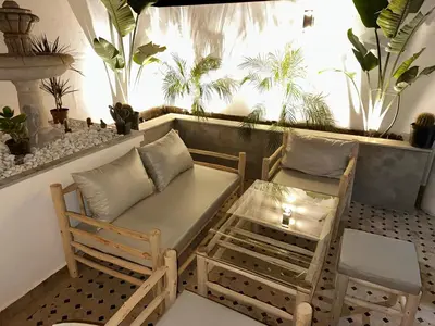 a balcony with a couch and chairs and plants at Duplex Sur Marrakech Guéliz in Marrakech