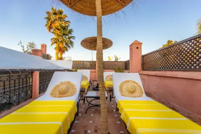 a patio with yellow and white chairs and an umbrella at Dar Charkia in Marrakech