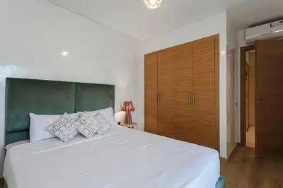 a bedroom with a white bed and a wooden closet at appartement- Marrakech-Sapphire in Marrakech