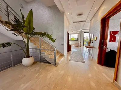 a hallway with a potted plant and a staircase at Villa ARGANA 6 chambres avec piscine jacuzzi et hammam à Argan Golf 10 min du centre in Marrakech