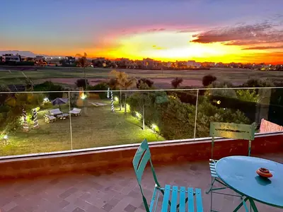 a balcony with a table and chairs and a sunset at Villa ARGANA 6 chambres avec piscine jacuzzi et hammam à Argan Golf 10 min du centre in Marrakech