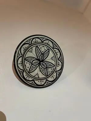 a black plate with a flower design on a ceiling at Red Vibes Hostel Marrakech in Marrakech