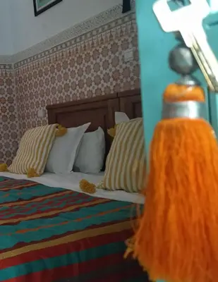 a bedroom with a bed with pillows and a orange blanket at Riad Dar Mamouni in Marrakech