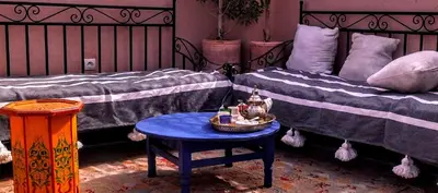 a room with two beds and a blue table with a table at Riad Dar Mamouni in Marrakech