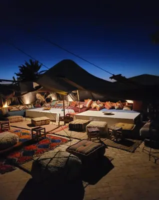 a patio with tables and chairs and umbrellas at night at Eden Lodges & SPA-Boutique Hôtel de Luxe in Marrakech