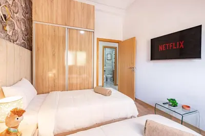 a bedroom with two beds and a tv on the wall at Stylish Cozy Appartement in marrakech with Pool in Marrakech