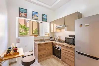 a kitchen with white walls and wooden cabinets at Stylish Cozy Appartement in marrakech with Pool in Marrakech