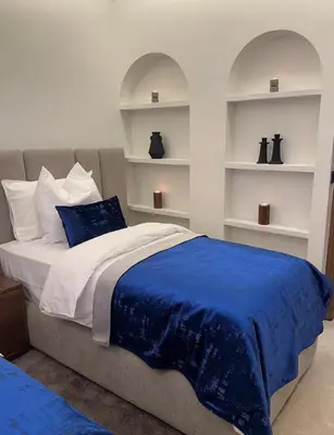 a bedroom with a bed with blue sheets and shelves at Prestige cocon in Marrakech