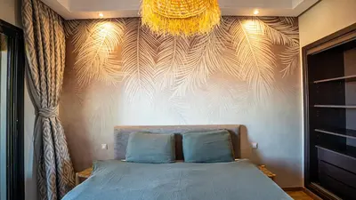 a bedroom with a bed and a wall with a chandelier at Grand T2, terrasse au coeur de Gueliz in Marrakech