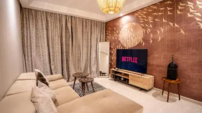 a living room with a couch and a tv at Grand T2, terrasse au coeur de Gueliz in Marrakech