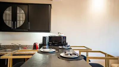 a kitchen with a table with plates and a microwave at Grand T2, terrasse au coeur de Gueliz in Marrakech
