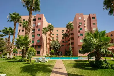 a large apartment building with a pool and palm trees at Artisan's Hideaway Marrakech in Marrakech