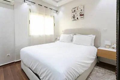 a white bedroom with a large bed and a window at Artisan's Hideaway Marrakech in Marrakech