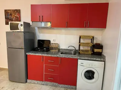 a kitchen with red cabinets and a washing machine at Le Marrakchi 37 au coeur de l'hivernage pour les familles acte de mariage obligatoire in Marrakech