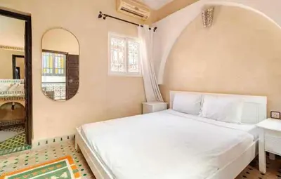 a bedroom with a white bed and a mirror at Riad Amani in Marrakech