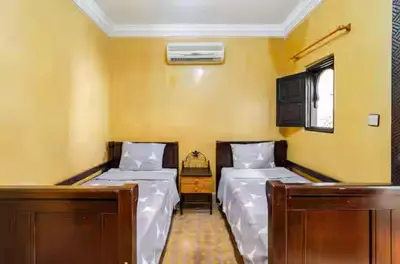two beds in a room with yellow walls at Riad Amani in Marrakech