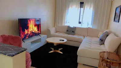 a living room with a white couch and a tv at Hivernage Cosy in Marrakech