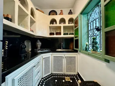a kitchen with white and green cabinets and a window at Riad Dar Najwa in Marrakech