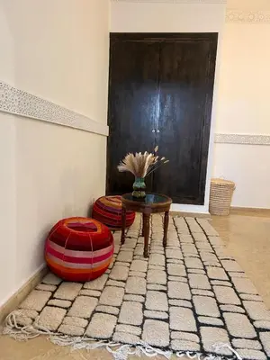 a living room with a table and two ottomans at Riad de charme avec piscine rooftop in Marrakech