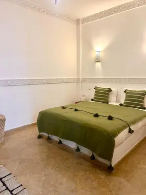 a bedroom with a large bed with green sheets and pillows at Riad de charme avec piscine rooftop in Marrakech