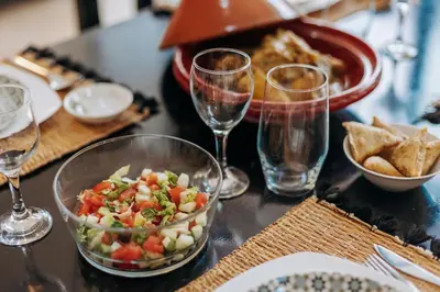 a table with a bowl of salad and glasses of wine at Riad de charme avec piscine rooftop in Marrakech