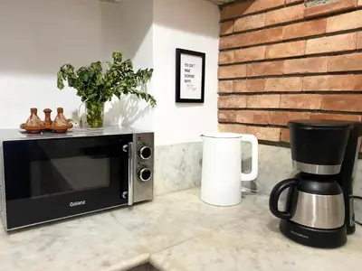 a microwave sitting on a counter next to a coffee maker at L'Alchimiste - Riad Entier à 10 minutes Jemaa El Fna in Marrakech