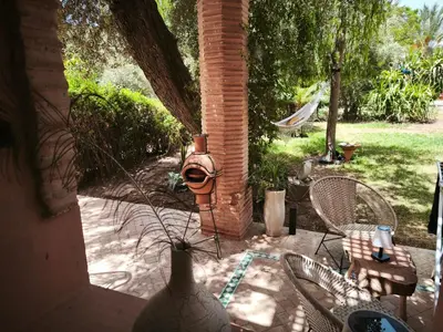 a patio with chairs and a vase with a plant at Nohaya - Palmeraie 2 Marrakech Un cadre verdoyant et reposant in Marrakech