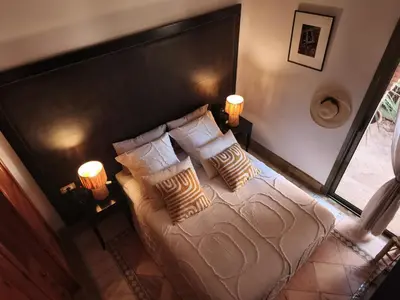 a bedroom with a bed with pillows and two lamps at Nohaya - Palmeraie 2 Marrakech Un cadre verdoyant et reposant in Marrakech