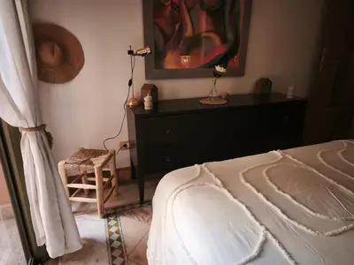 a bedroom with a bed and a dresser with a painting at Nohaya - Palmeraie 2 Marrakech Un cadre verdoyant et reposant in Marrakech
