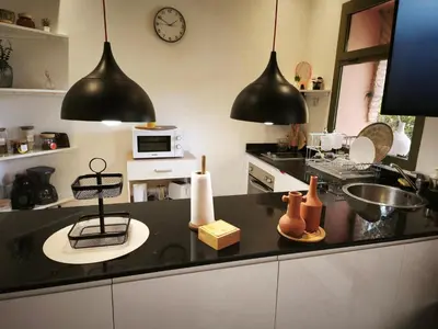 a kitchen with two black pendant lights above a counter at Nohaya - Palmeraie 2 Marrakech Un cadre verdoyant et reposant in Marrakech