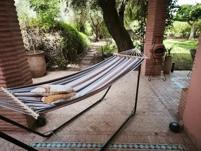 a hammock on a patio in a yard at Nohaya - Palmeraie 2 Marrakech Un cadre verdoyant et reposant in Marrakech