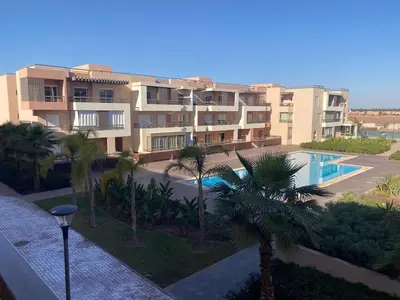 an apartment complex with a swimming pool and palm trees at Cozy apartment with pool Bd Mohamed 6 in Marrakech