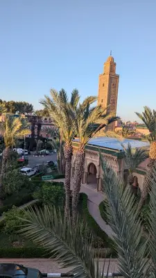 a view of a building with palm trees and a tower at Almohafidon room in Marrakech