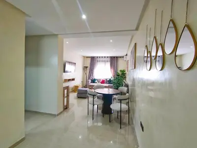 a dining room and living room with a table and chairs at Chic & Comfort Apartment in Marrakech